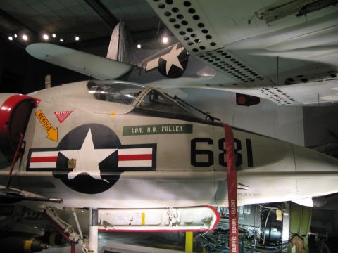 1991 Ford LTD Crown Victoria - gray Navy jet numbered 681 with a bubble cockpit, star insignia and red rescue arrow is shown in a museum.