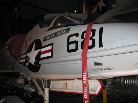 1991 Ford LTD Crown Victoria - forward fuselage of gray Navy jet 681 shows its cockpit, star-and-bars insignia and red remove-before-flight streamer.