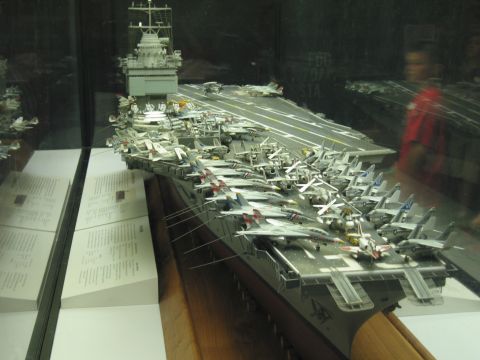 1991 Ford LTD Crown Victoria - detailed scale model of an aircraft carrier packed with model jets sits behind glass in a museum exhibit.