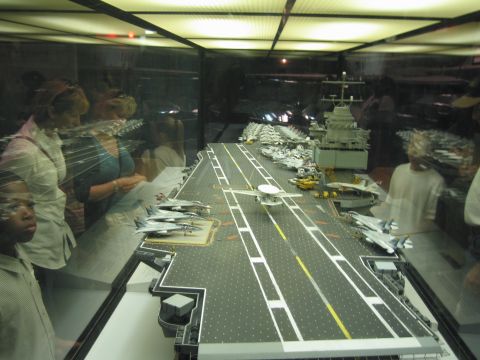 1991 Ford LTD Crown Victoria - lengthwise view down an aircraft carrier model's flight deck shows parked jets and reflections of museum visitors.