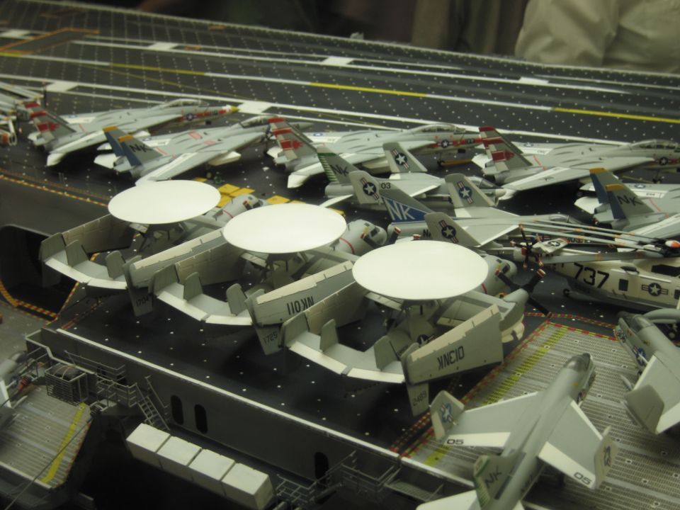 Scale model carrier deck packed with radar-dome and gray Navy aircraft