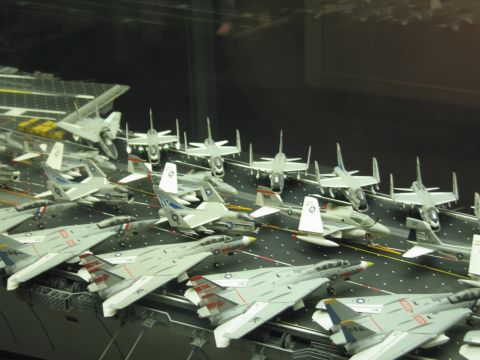 1991 Ford LTD Crown Victoria - model aircraft carrier deck densely arranged with gray Navy jets, displayed behind a glass case.