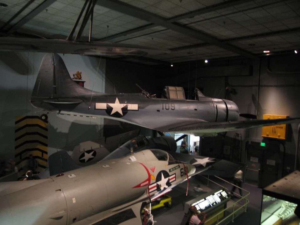 Gray Navy aircraft number 109 with star insignia hung above other planes in museum