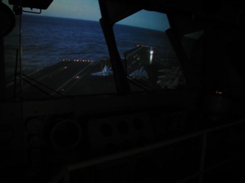 1991 Ford LTD Crown Victoria - dark ship bridge interior with instrument panels and windows overlooking the sea and a lit deck.