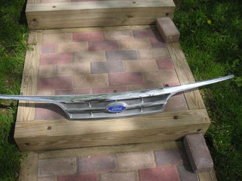 1997 Ford Crown Victoria - A chrome and silver Ford grille with the blue oval emblem is displayed on outdoor wooden steps.
