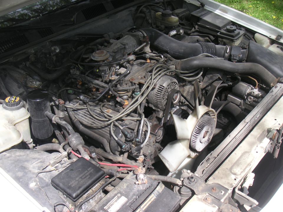 1997 Ford Crown Victoria engine bay with visible V8 engine, fan, and radiator. White exterior