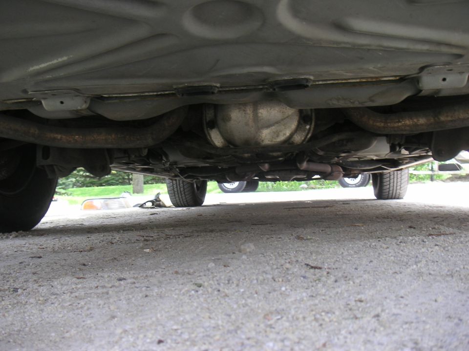 Underside rear view showing solid axle housing and dual rusty exhaust pipes