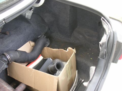 1997 Ford Crown Victoria - The trunk of a car contains a cardboard box with air intake components and other miscellaneous items.
