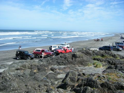 2005 Jeep Wrangler - Several vehicles are parked on a rocky shore with the ocean in the background.