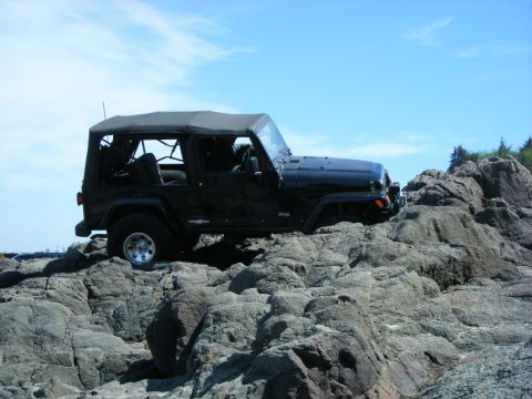 2005 Jeep Wrangler - A black Jeep Wrangler navigates a rocky coastal path on a clear day.