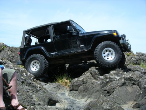 2005 Jeep Wrangler - A black Jeep Wrangler navigates a rocky trail under a clear blue sky.