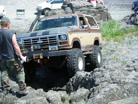 2005 Jeep Wrangler - This lifted Ford Bronco is tackling a challenging off-road course with large tires and a winch.