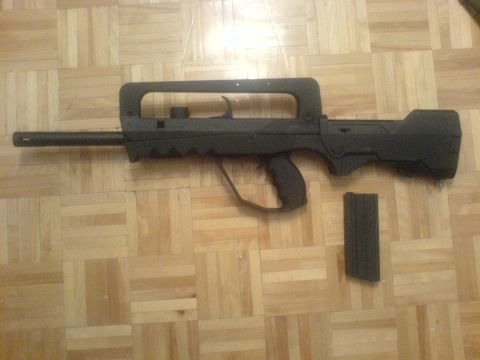 1985 Ford Bronco - A FAMAS assault rifle with its magazine lies on a wooden floor.