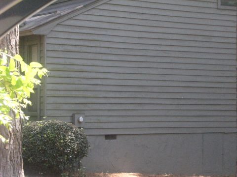 1992 Ford F-150 - The image shows the exterior of a building with gray siding, a tree, and a bush in front.