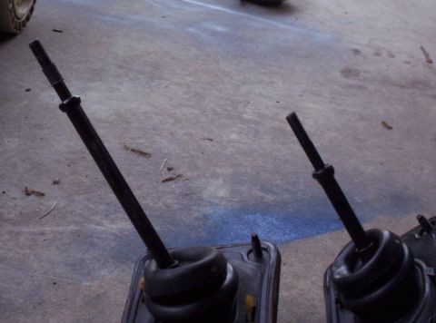 1995 Ford Probe - Two car gear shift levers are shown resting on a concrete surface, possibly during a repair or replacement process.