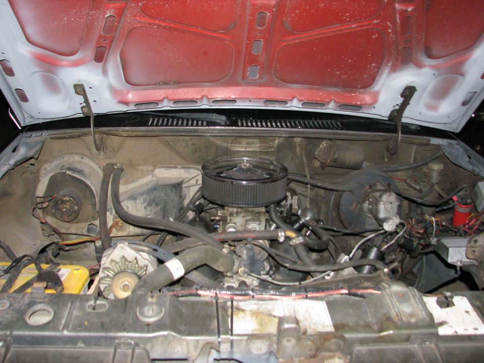 V8 engine bay with red firewall, chrome air cleaner and yellow battery tray