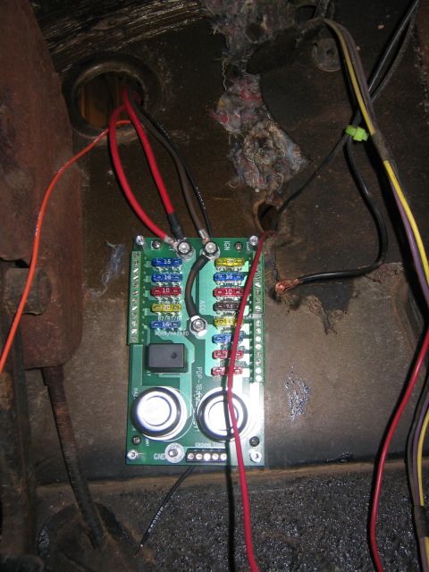1979 Ford Bronco - A close-up view of a fuse block and wiring harness mounted to a metal surface, likely in a vehicle's interior.
