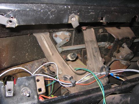 1979 Ford Bronco - This image shows the underside of a dashboard, focusing on the brake and clutch pedal assembly and associated wiring. Various metal bracket…