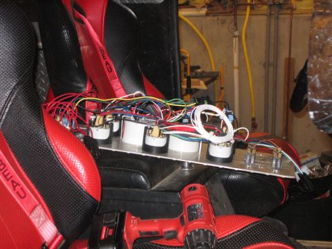 1979 Ford Bronco - A close-up view of a custom dashboard with gauges and wiring, installed in a red and black racing seat.