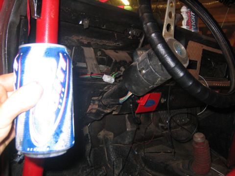 1979 Ford Bronco - A hand holds a can of Coors Light next to the steering column of a vehicle. The interior shows the steering wheel, dashboard, and various w…