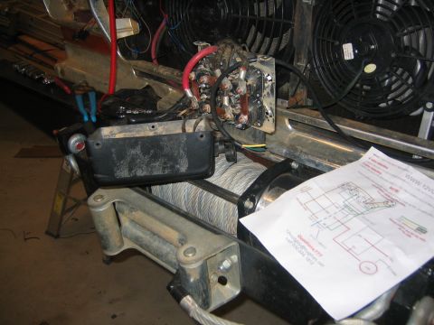 1979 Ford Bronco - A close-up view of a winch motor and wiring with a wiring diagram laid out in front of it. The winch appears to be installed on a vehicle,…