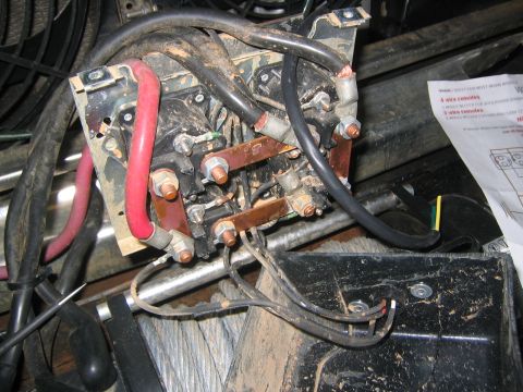 1979 Ford Bronco - A close-up view of a dirty, complex electrical relay and wiring assembly, likely for a winch, with thick red and black cables connected to…