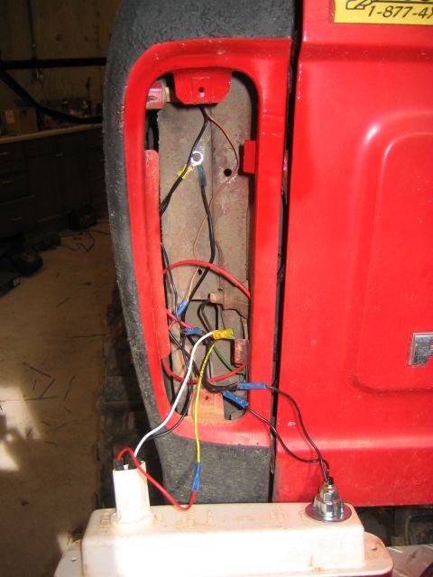 1979 Ford Bronco - Close-up view of the wiring harness for a red vehicle's taillight assembly. Wires are connected with blue and yellow crimp connectors, and…