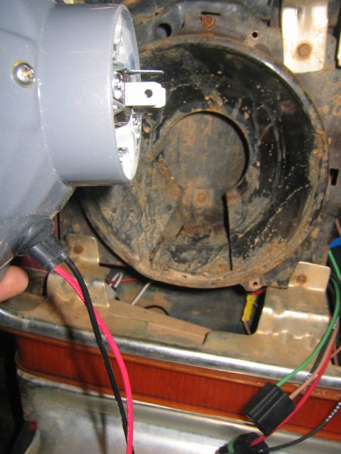 1979 Ford Bronco - A close-up view shows the electrical connector and wiring for a headlight assembly being worked on, with the vehicle's rusty headlight hous…