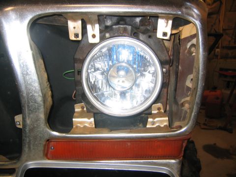 1979 Ford Bronco - Close-up view of the driver's side headlight assembly and amber turn signal on a vintage vehicle. The headlight is a round, clear lens with…