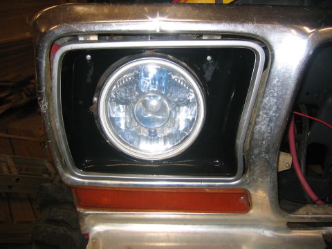 1979 Ford Bronco - A close-up view of the front headlight assembly of a vintage vehicle, featuring a round headlight within a black housing, surrounded by chr…