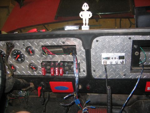 1979 Ford Bronco - The interior dashboard of a vehicle features a diamond plate metal panel with multiple gauges, switches, and a CB radio. A white Michelin M…