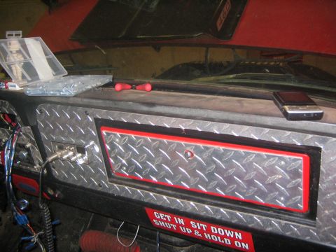 1979 Ford Bronco - A close-up interior view of a vehicle's dashboard shows a diamond plate panel with red trim, a CB radio, and a cell phone resting on the da…