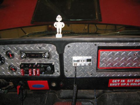 1979 Ford Bronco - The interior dashboard of a vehicle features a CB radio, several toggle switches, and a car stereo. A small Michelin Man figurine stands on…