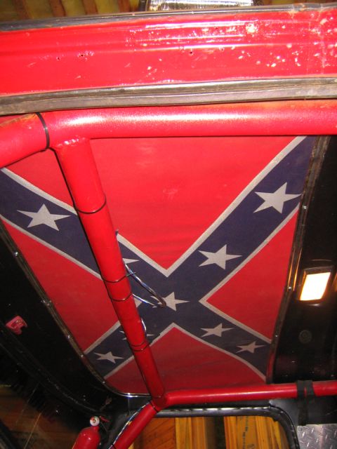1979 Ford Bronco - The interior of a vehicle shows a roll cage painted red and a headliner decorated with a Confederate flag pattern. A fire extinguisher is v…