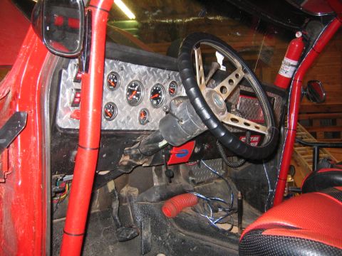 1979 Ford Bronco - The interior of a red off-road vehicle, likely a modified Bronco, features a diamond plate dashboard with multiple gauges, a custom steerin…