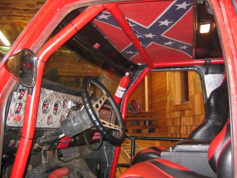 1979 Ford Bronco - The interior of a red off-road vehicle, possibly a Ford Bronco, features a roll cage, a dashboard with multiple gauges, a steering wheel, a…