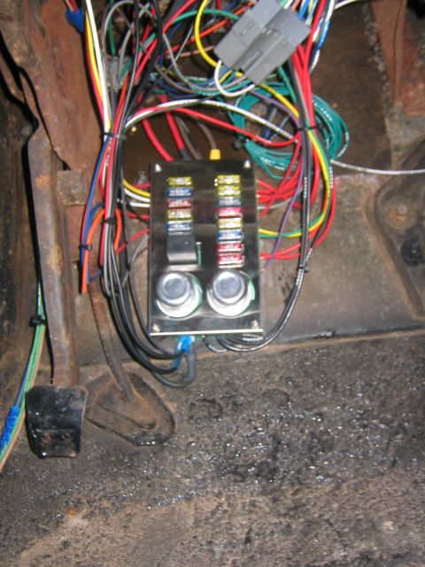 1979 Ford Bronco - A close-up view of a fuse box and wiring harness installed in the interior of a vehicle, likely a classic Ford Bronco, with a brake pedal v…