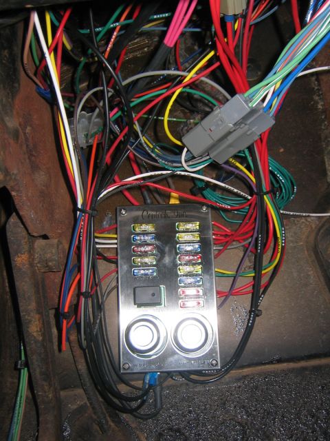 1979 Ford Bronco - A close-up view of a complex automotive wiring harness and a Centech Inc. fuse block with multiple fuses and two illuminated buttons. The w…