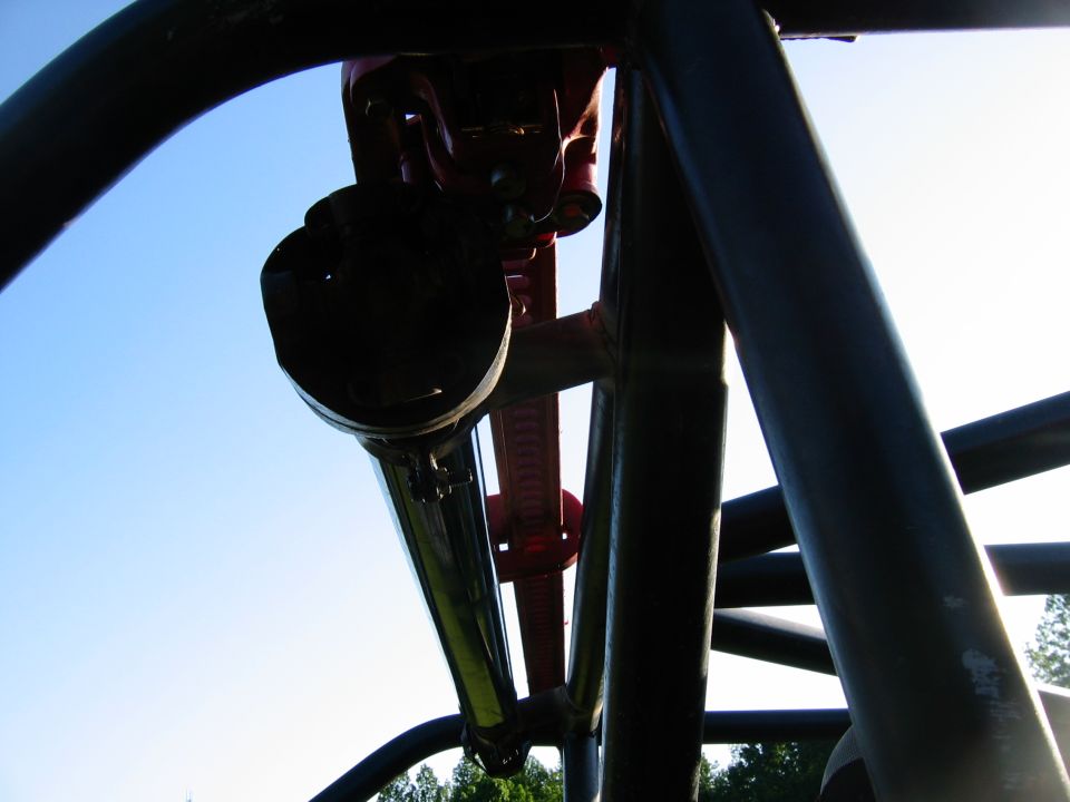 Underside of a roller coaster structure against a blue sky.