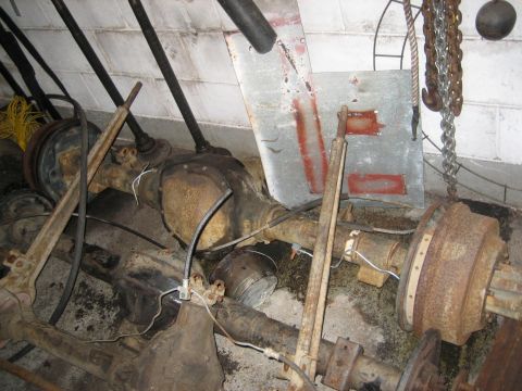 1990 Ford Bronco - Several rusty Ford Bronco rear axles are stored in a garage. The axles are arranged in a pile, with some parts still attached, including br…