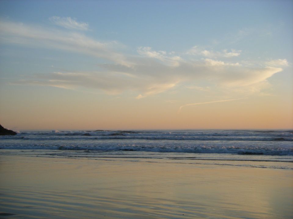 Beach sunset with gentle waves and colorful sky.