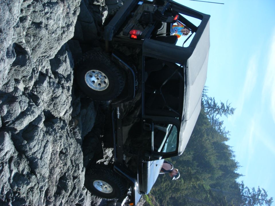 Black Jeep Wrangler tilted on a rocky incline.