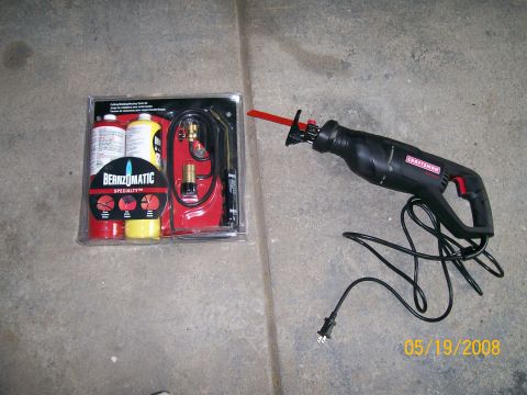 1995 Mercury Grand Marquis - A packaged BernzOmatic Specialty cutting/welding/brazing torch kit with red and yellow gas cylinders sits on a concrete floor beside a cord…