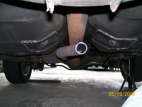 1995 Mercury Grand Marquis - The underside of a vehicle shows the exhaust system, including a muffler and tailpipe, and the rear suspension components. The vehicle is s…
