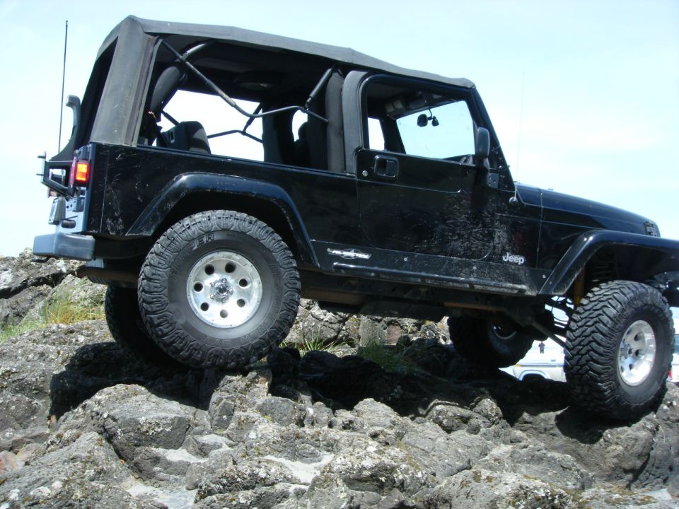 Black Jeep Wrangler off-roading on large rocks
