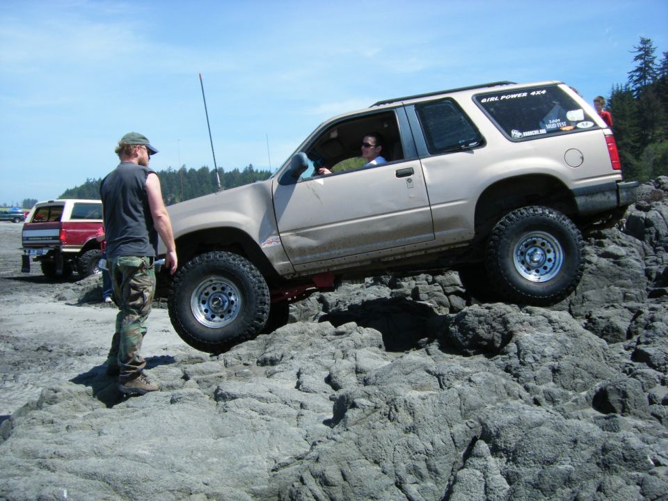 Tan 1994 Ford Explorer off-roading on rocks with "Girl Power 4x4" sticker.