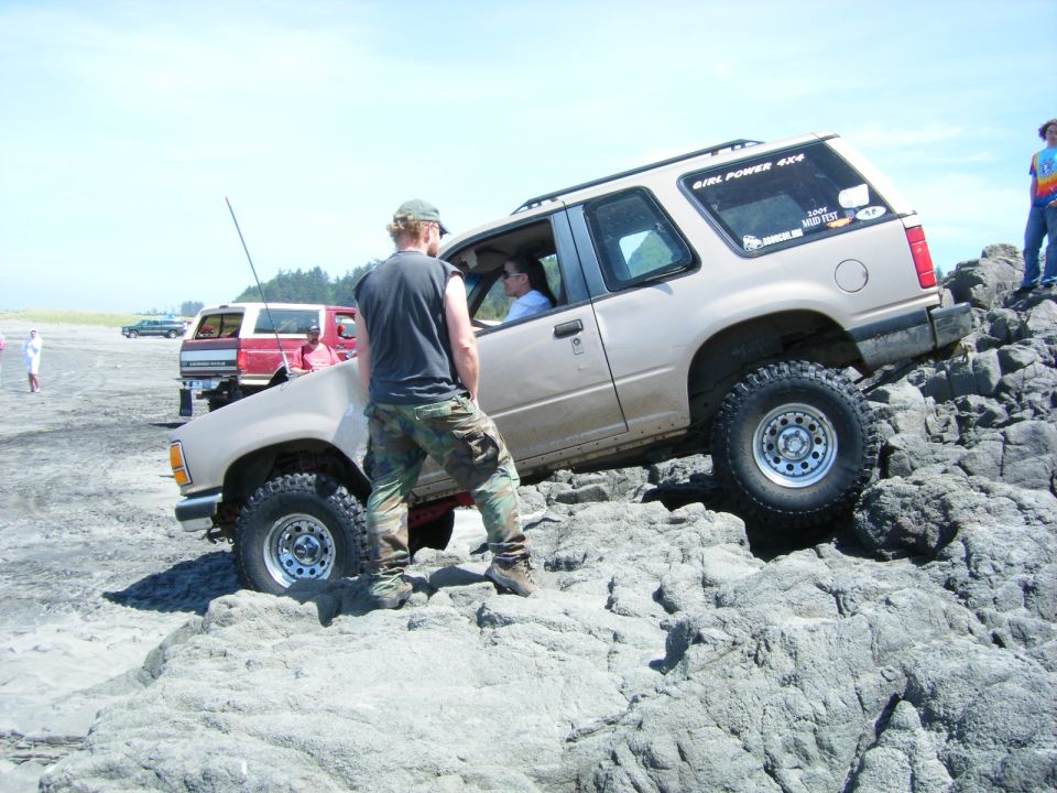 Tan 1994 Ford Explorer off-roading on rocks, driver's side visible.