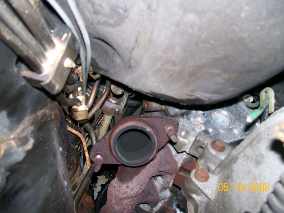 Rusty exhaust manifold outlet flange with studs exposed after downpipe removal
