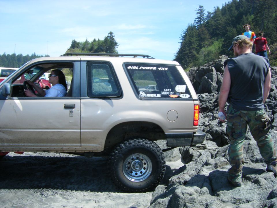 Tan 1994 Ford Explorer parked on a rocky beach with a woman driving.