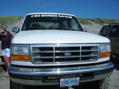 1994 Ford Explorer - A white Ford truck with a "2 BIG BRONCOS 4x4 CLUB" sticker on the windshield is parked on a sandy beach next to another SUV.